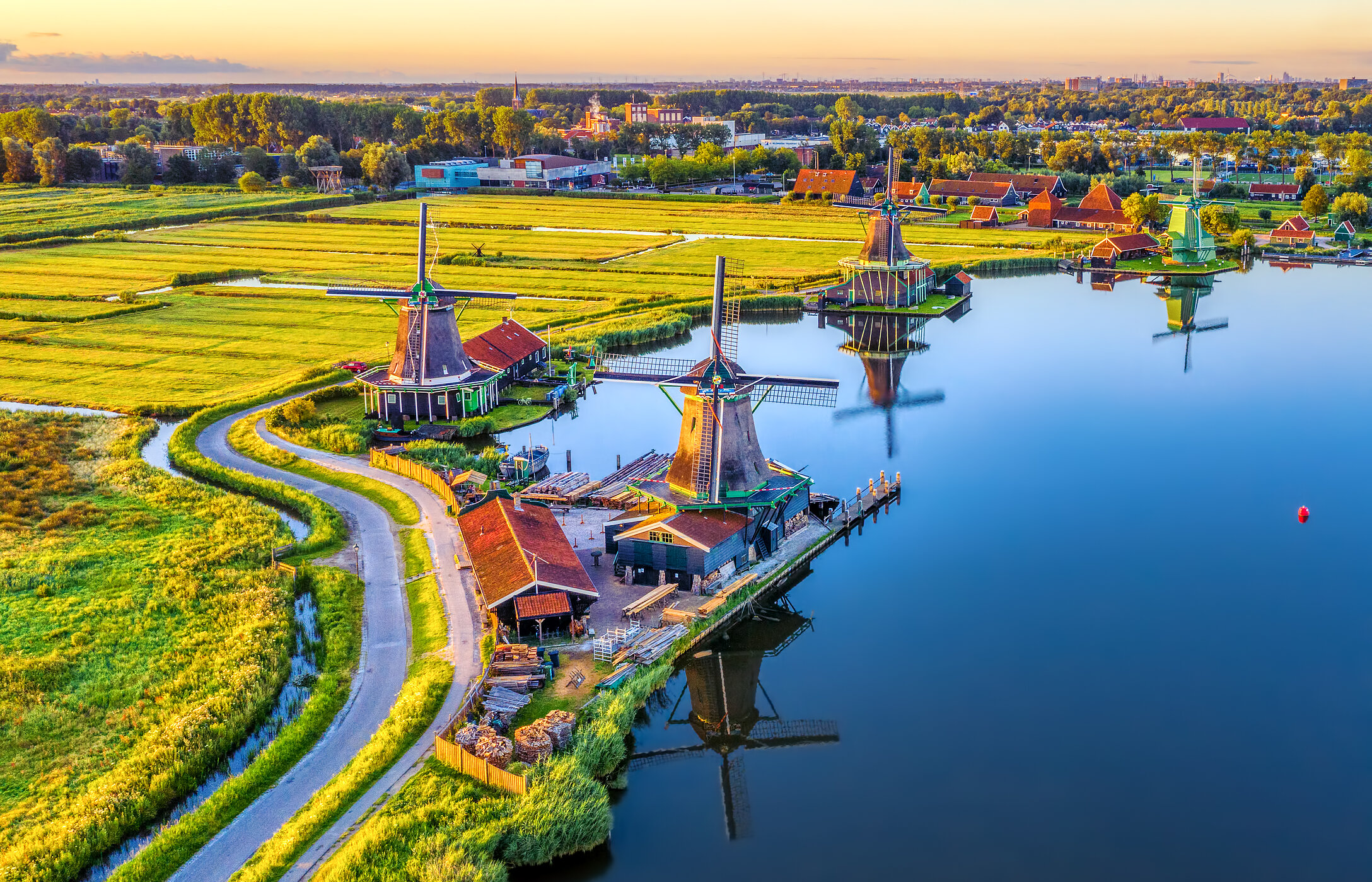 Vista aérea de Zaandam, con sus típicos molinos junto a un lago, rodeados de campos verdes.