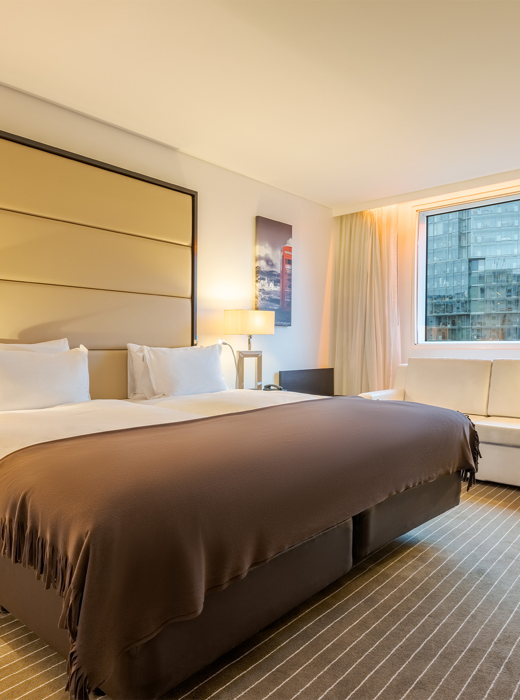 El Twin Deluxe del Pestana Chelsea Bridge tiene dos camas juntas, mesita, sofá, lámparas y ventanas con cortinas