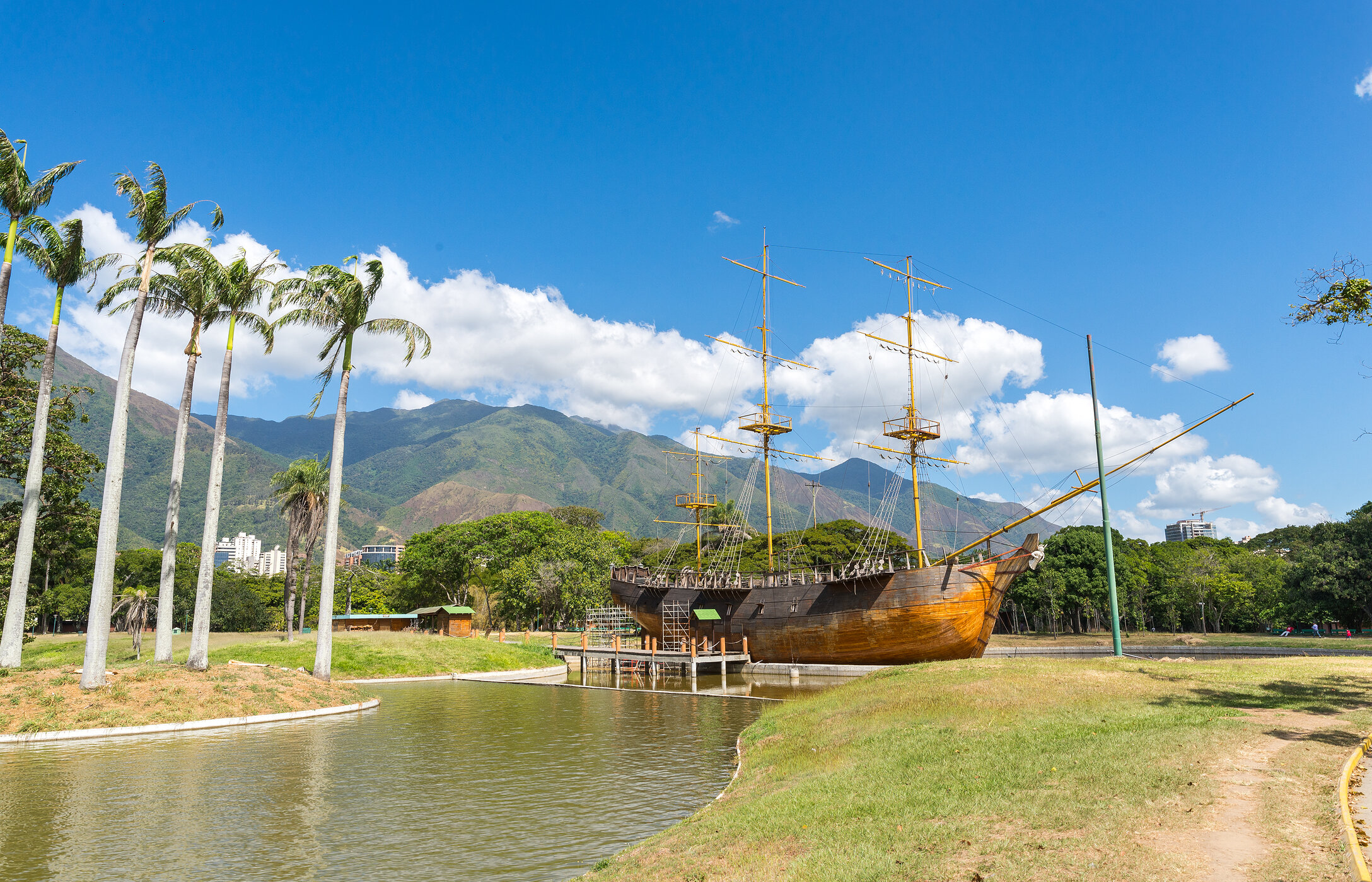 Parque del Este, situado en Caracas, con un lago y un barco histórico anclado, con montañas y vegetación al fondo