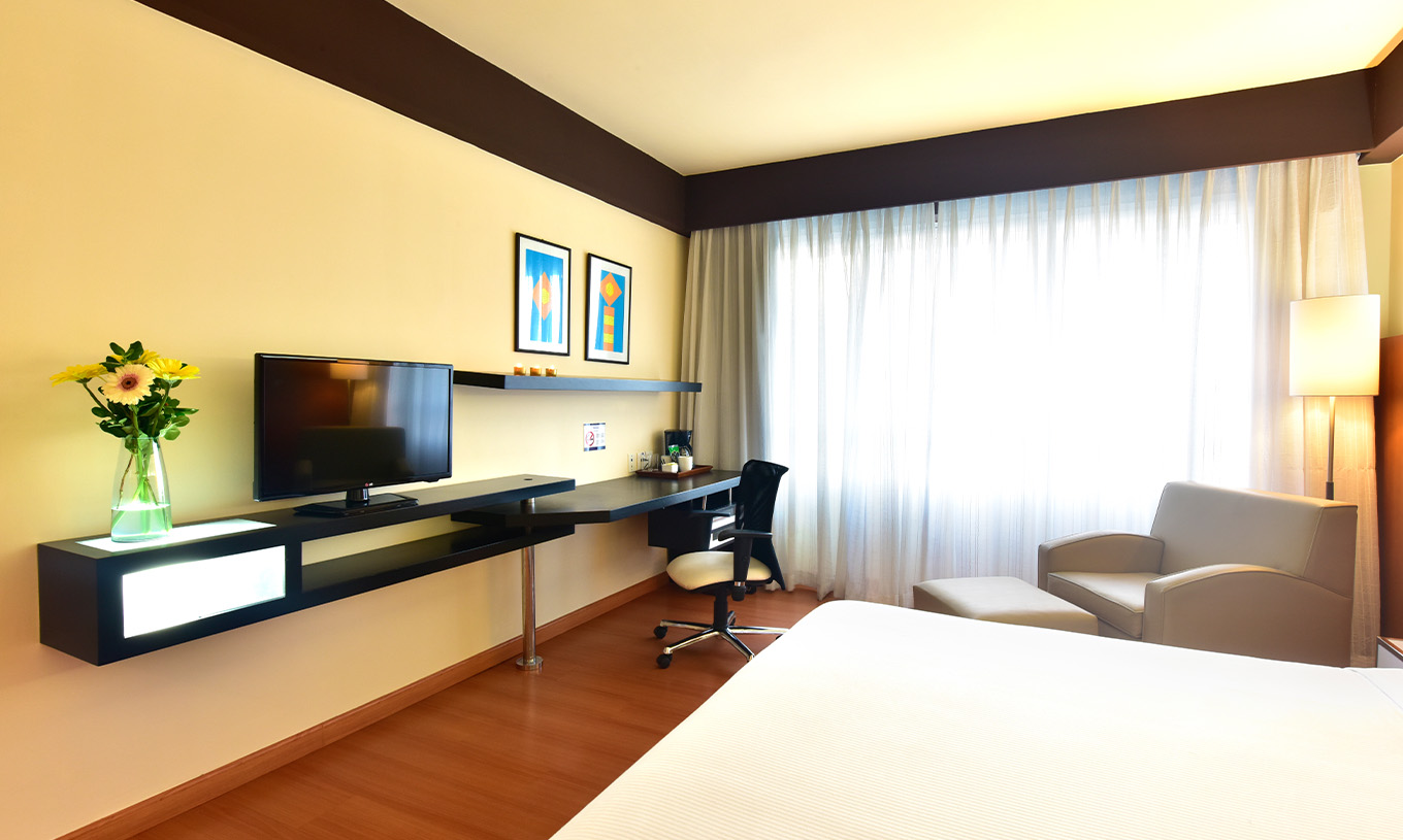 La habitación Twin Superior del Pestana Caracas tiene una televisión al fondo de la cama, una butaca, un escritorio y ventana