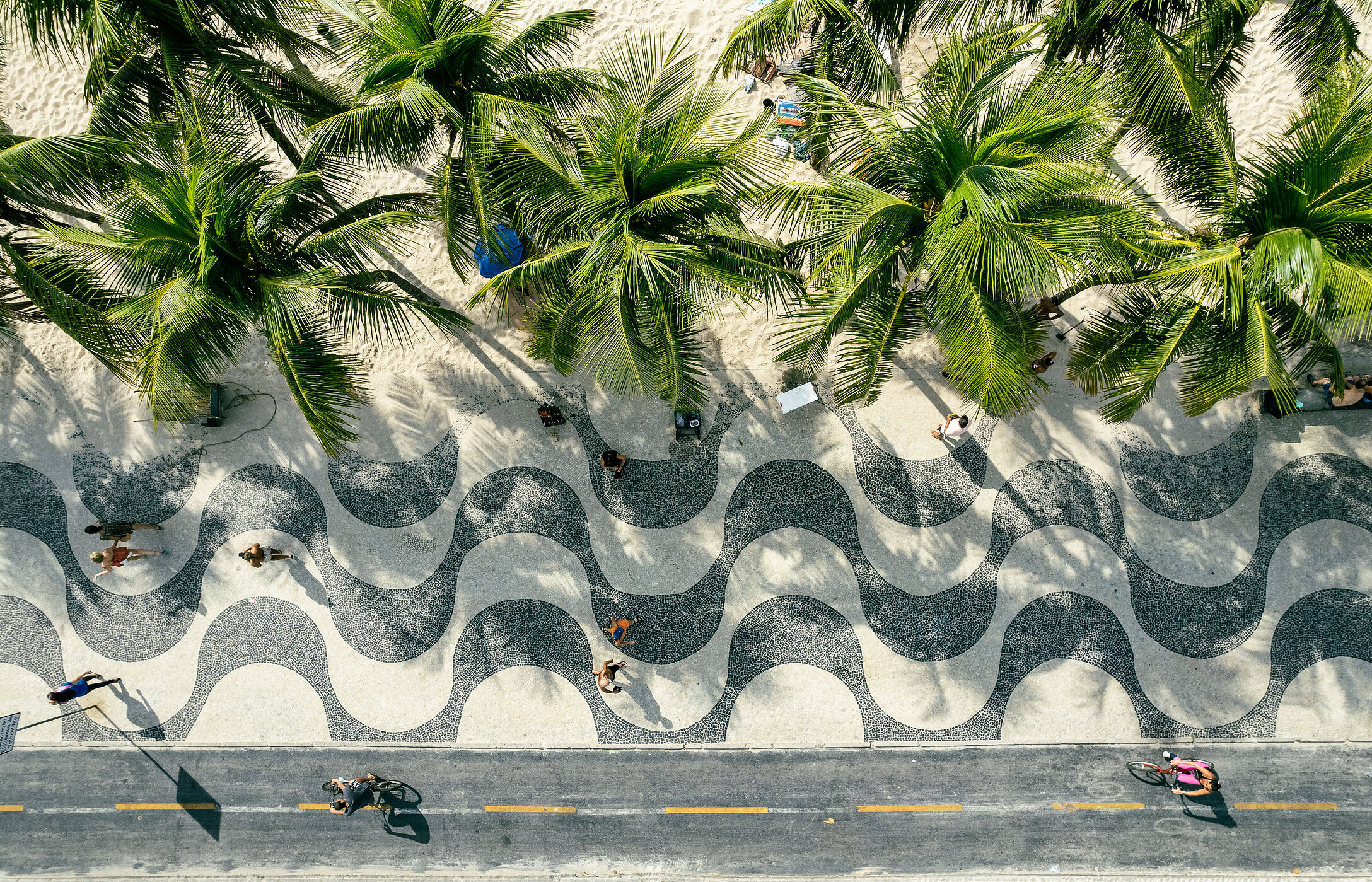 Luftaufnahme des Gehwegs der Avenida Atlântica mit Palmen und Sand vor dem Strand von Copacabana in Brasilien