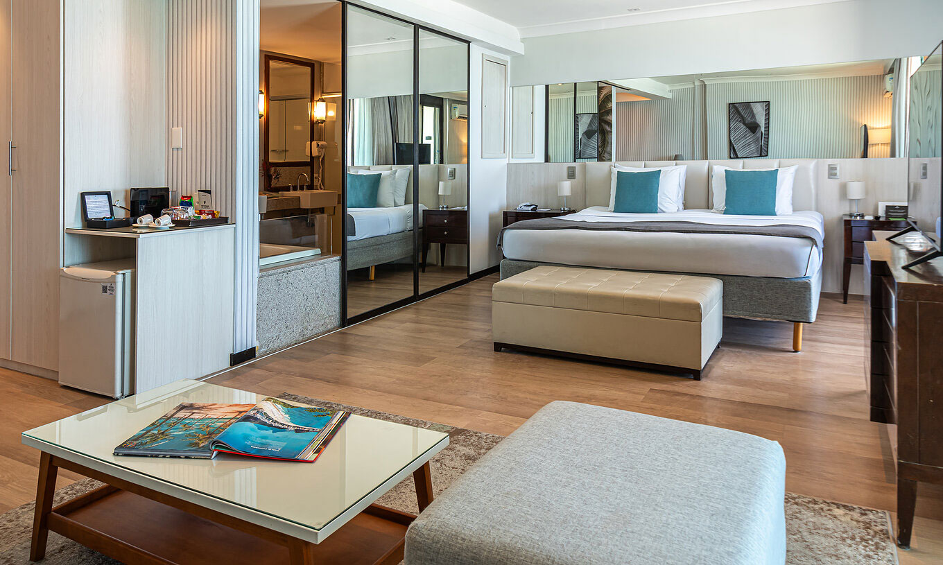La Suite Face à la Plage du Pestana Rio Atlântica a chambre moderne avec lit, miroir et coin salon.