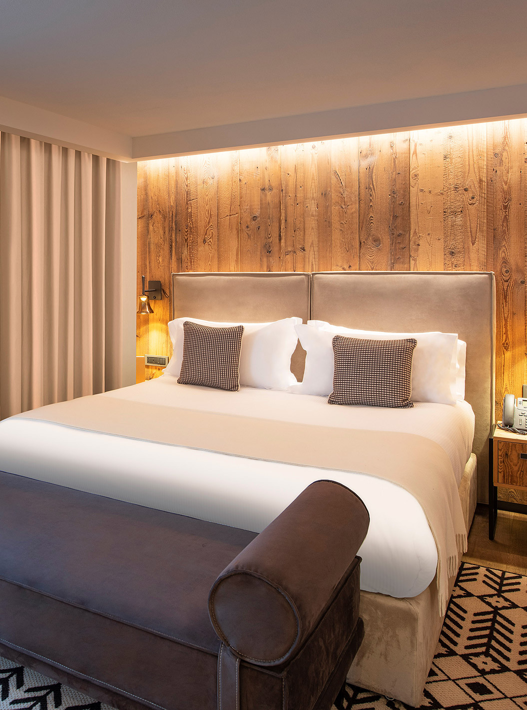 Chambre Deluxe au Le Massif Courmayeur avec grand lit, mur en bois éclairé et rideaux du sol au plafond