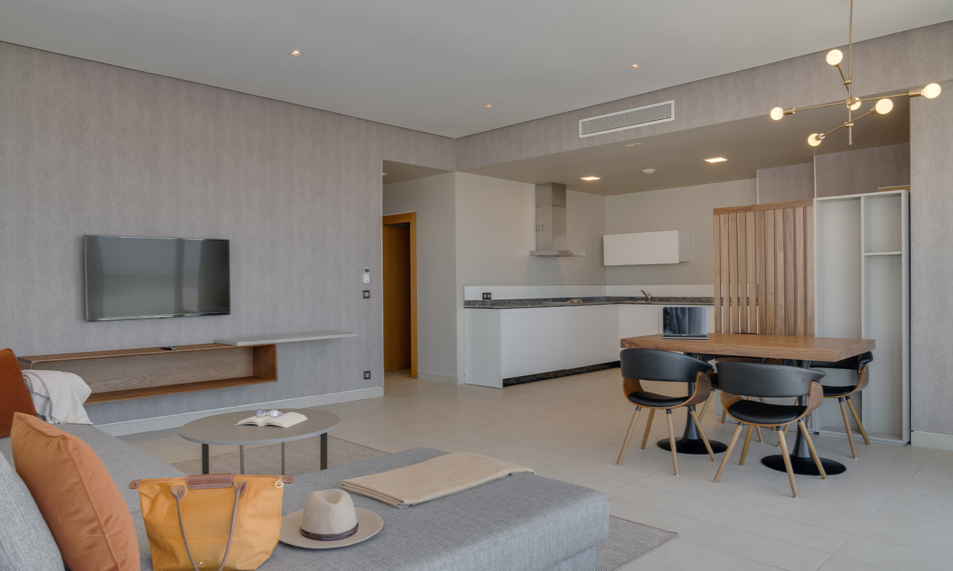 La Suite Familiale Corniche du Pestana Casablanca a un salon spacieux avec canapé, télévision, table à manger et kitchenette