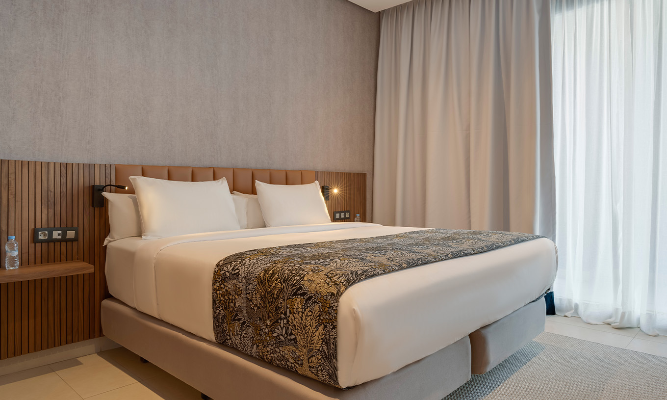 Suite Familiale vue latérale sur l'océan au Pestana Casablanca avec grand lit et rideaux clairs beiges