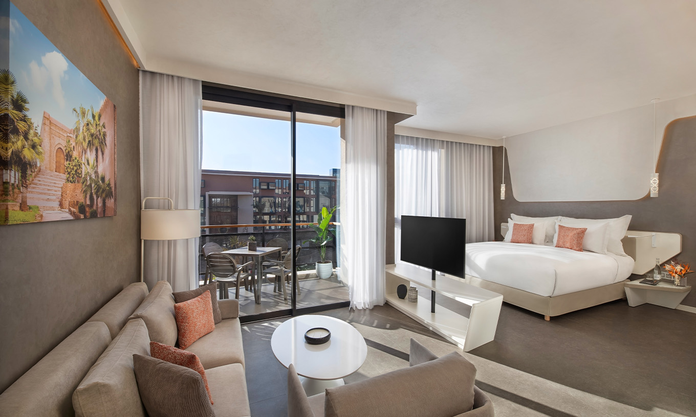La Junior Suite Avenue du Pestana CR7 Marrakech a un coin salon avec canapés et télévision, et un balcon