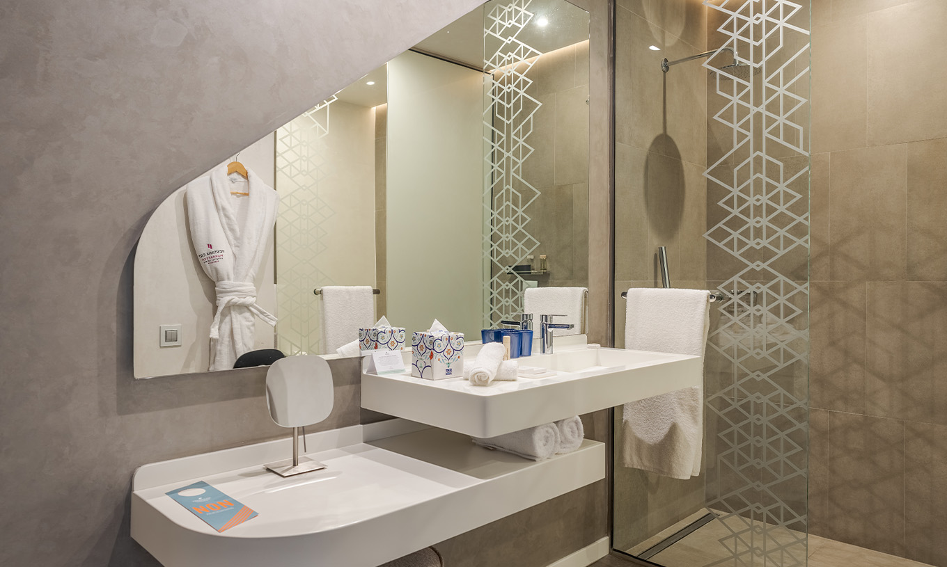 La Junior Suite du Pestana CR7 Marrakech a une salle de bain avec douche à l'italienne, lavabo et miroir