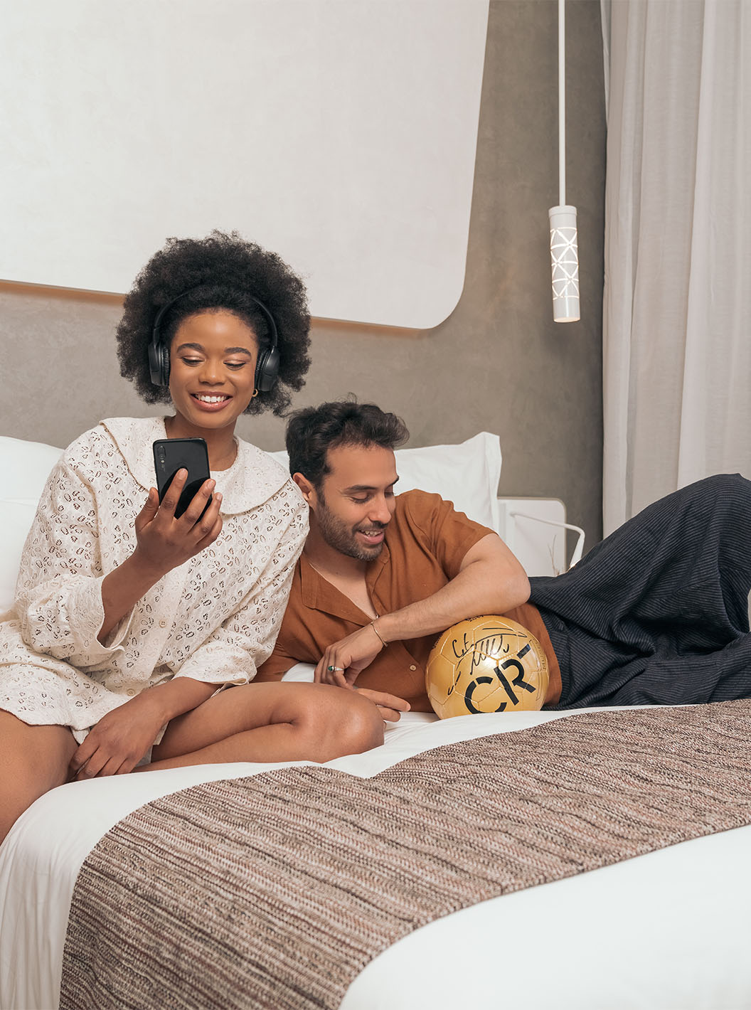 La chambre CR7 Superior du Pestana CR7 Marrakech a un lit double, un couple souriant, avec un ballon de football du CR7