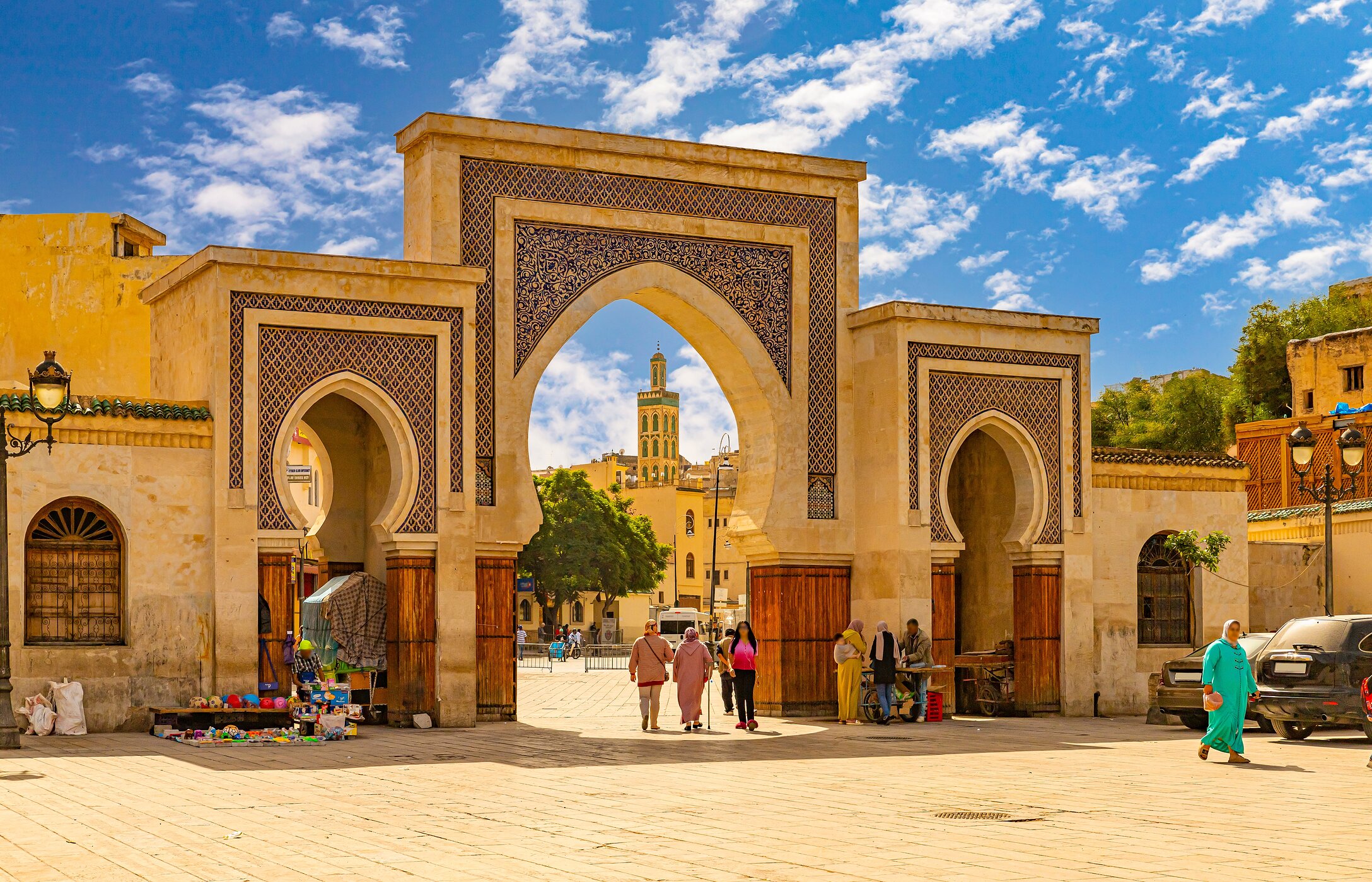 Arches typiques marocains à Fès, avec des carreaux couleur sable et des gens en habits traditionnels.