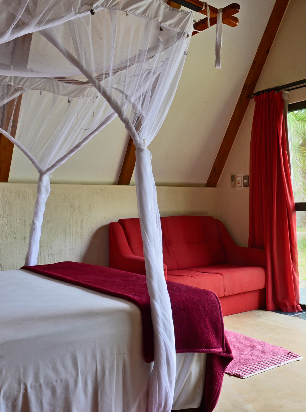 Le Bungalow Suite T2 du Pestana Bazaruto Lodge a un lit à baldaquin et vue sur le jardin et un canapé double sur le côté