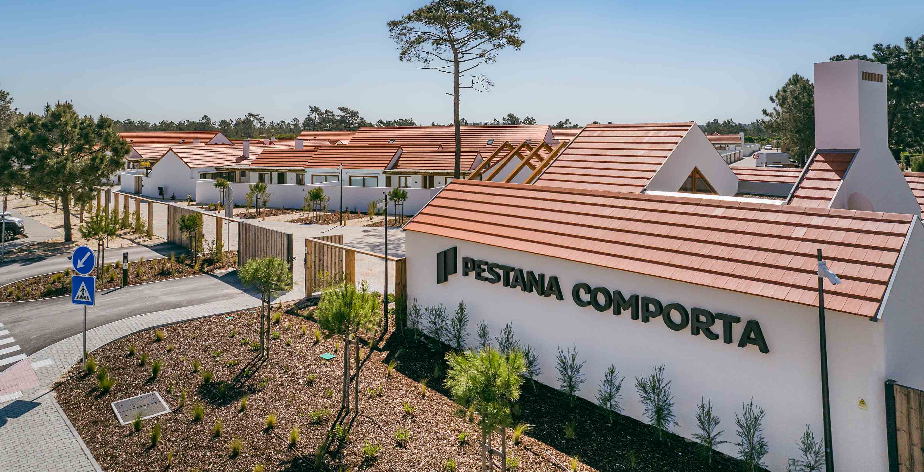 Vue du Pestana Comporta Village Residences, composé de villas aux toits rouges, entourées de végétation et d'arbres