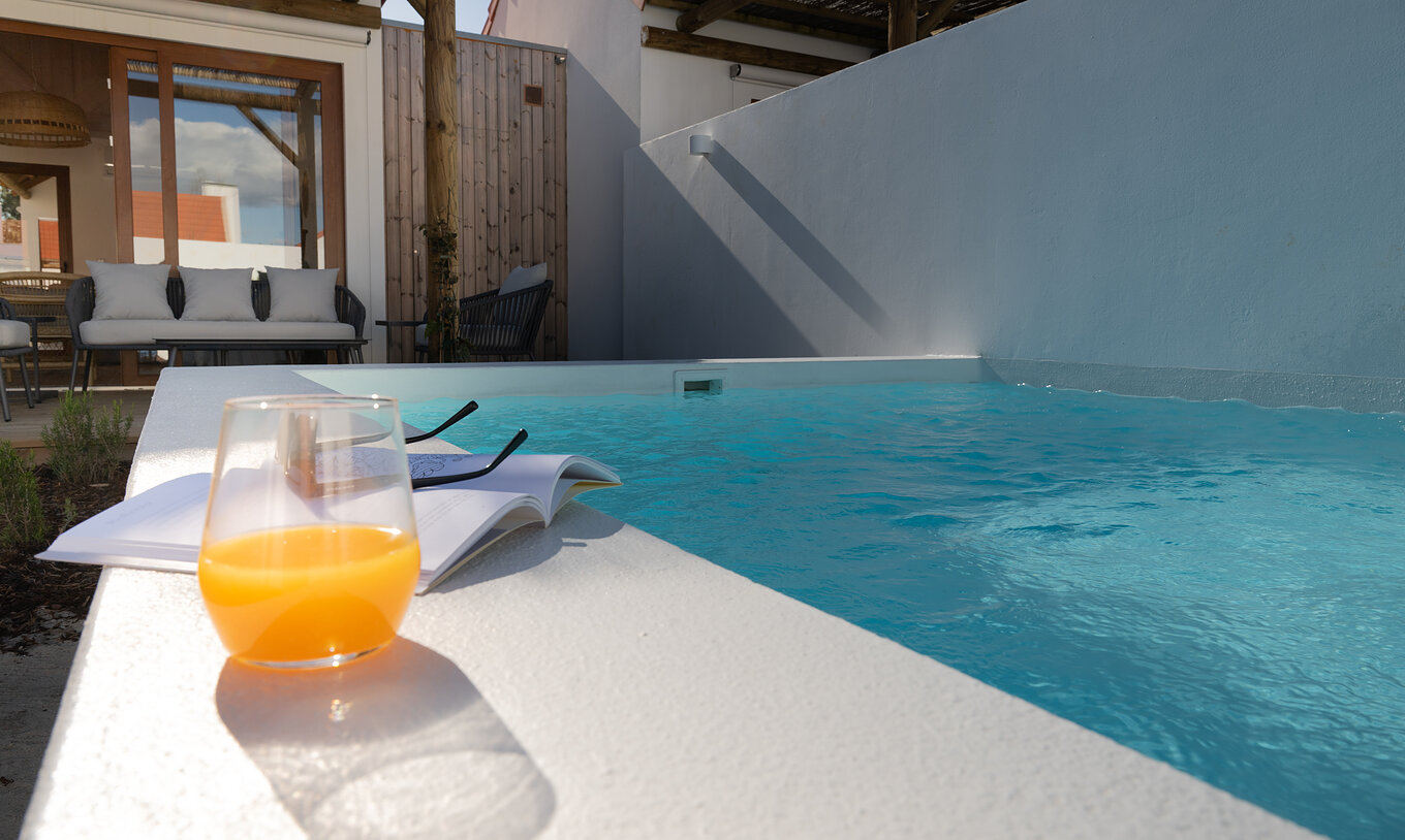 La Superior Green Villa du Pestana Comporta Village Residences dispose d'un patio avec un verre et un livre près la piscine
