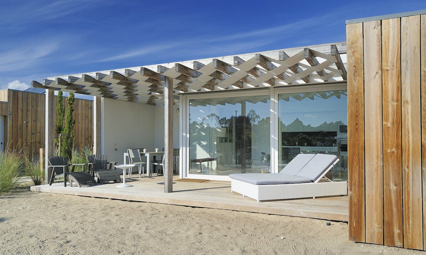 La Green Villa T3 du Pestana Tróia Eco Resort a une terrasse avec chaises longues, table et chaises