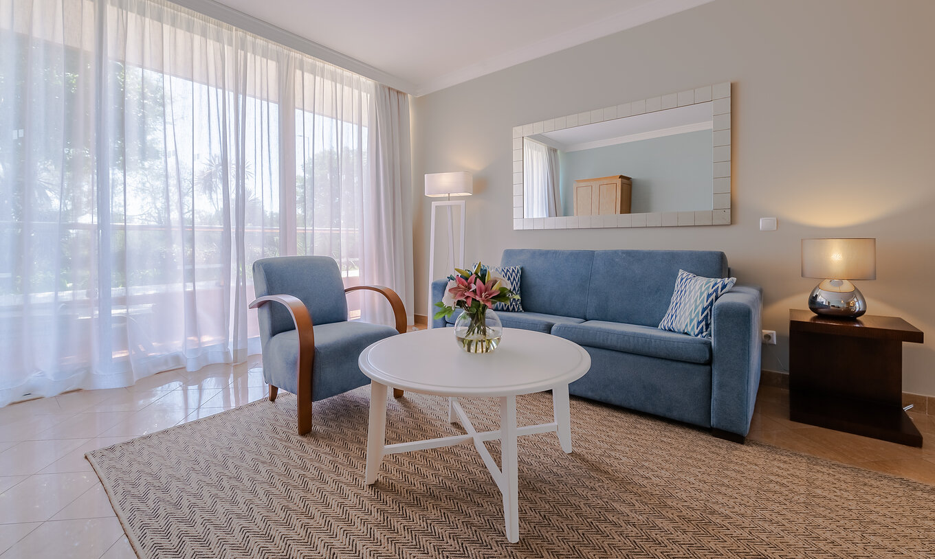 Le T1 - 1 Chambre du Pestana Alvor Park a un salon avec un canapé et un fauteuil bleus