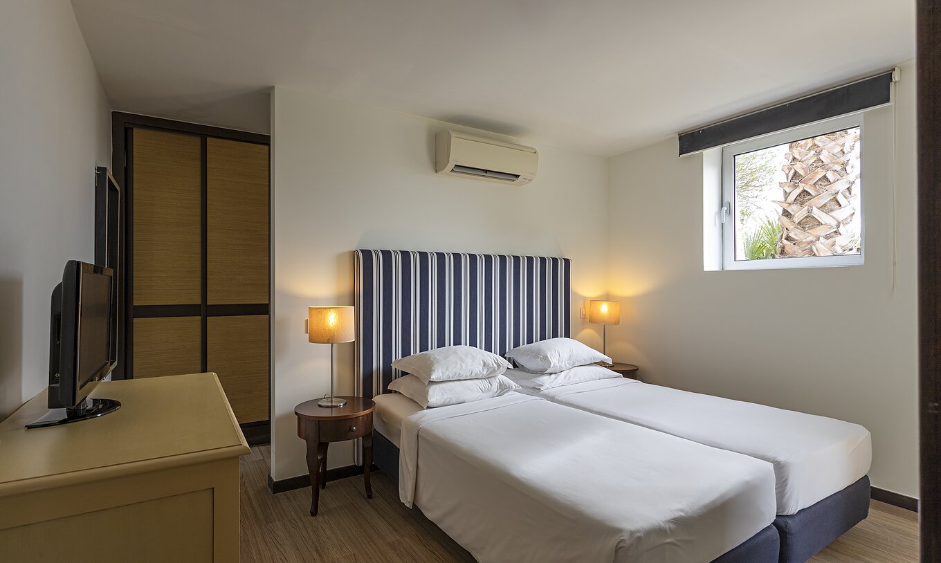 La suite Cliff T2 du Pestana Alvor Praia dispose d'une chambre avec un lit, une télévision, une armoire et la climatisation