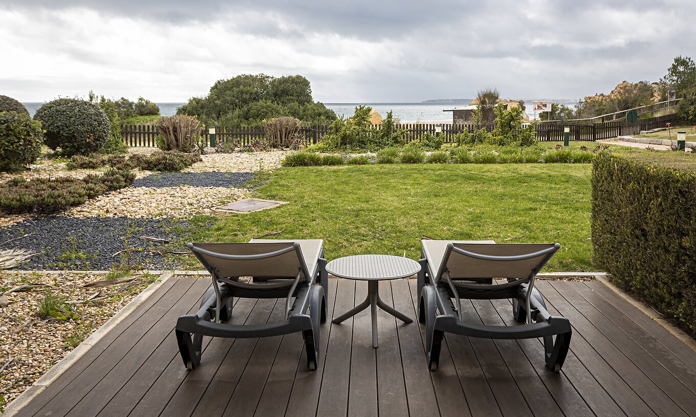 La suite Cliff T2 du Pestana Alvor Praia a un jardin avec pelouse, végétation, deux chaises longues et vue sur la plage