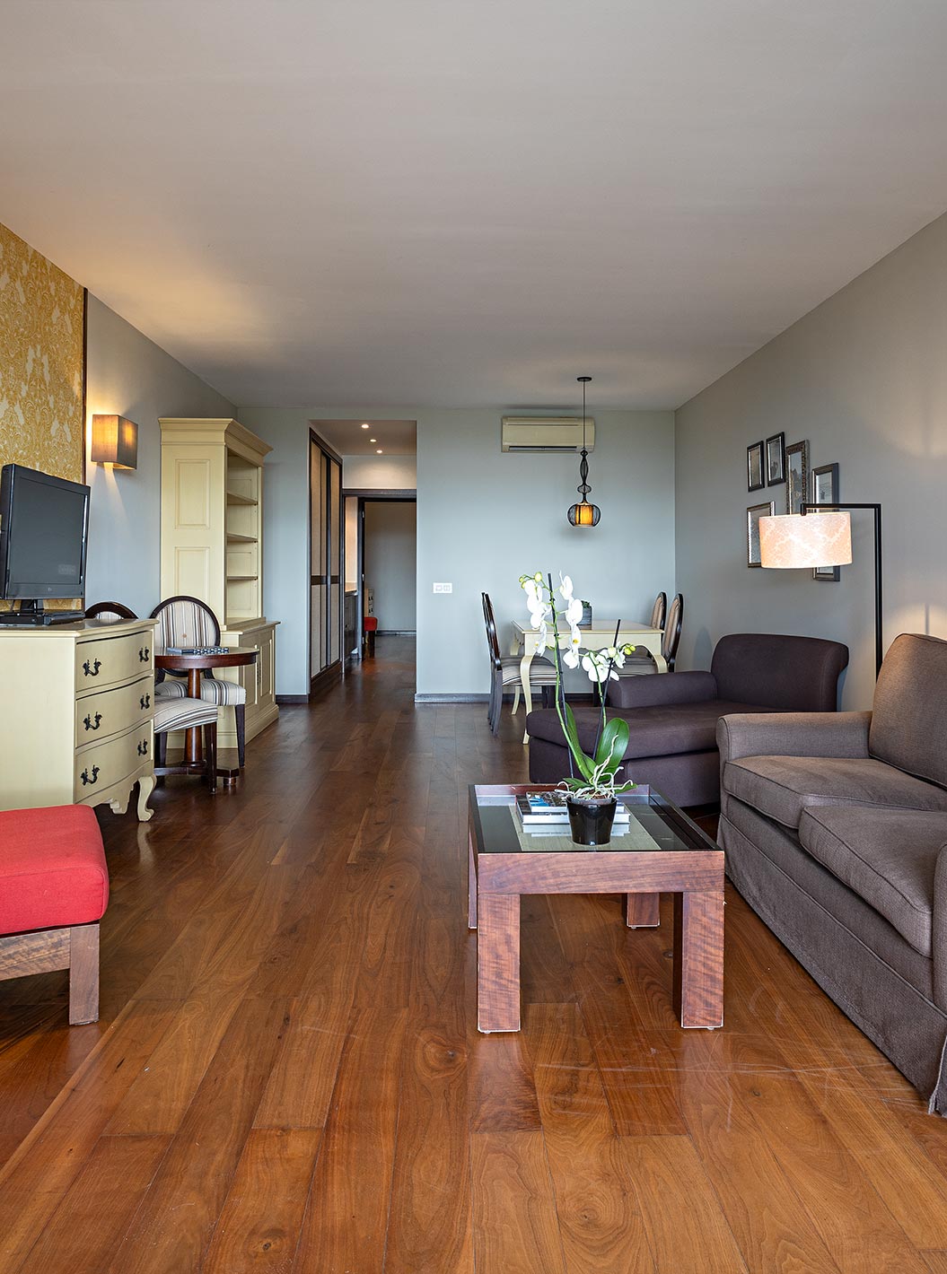 La suite Cliff T2 du Pestana Alvor Praia dispose d'un salon avec deux canapés, du papier peint, une télévision et une table