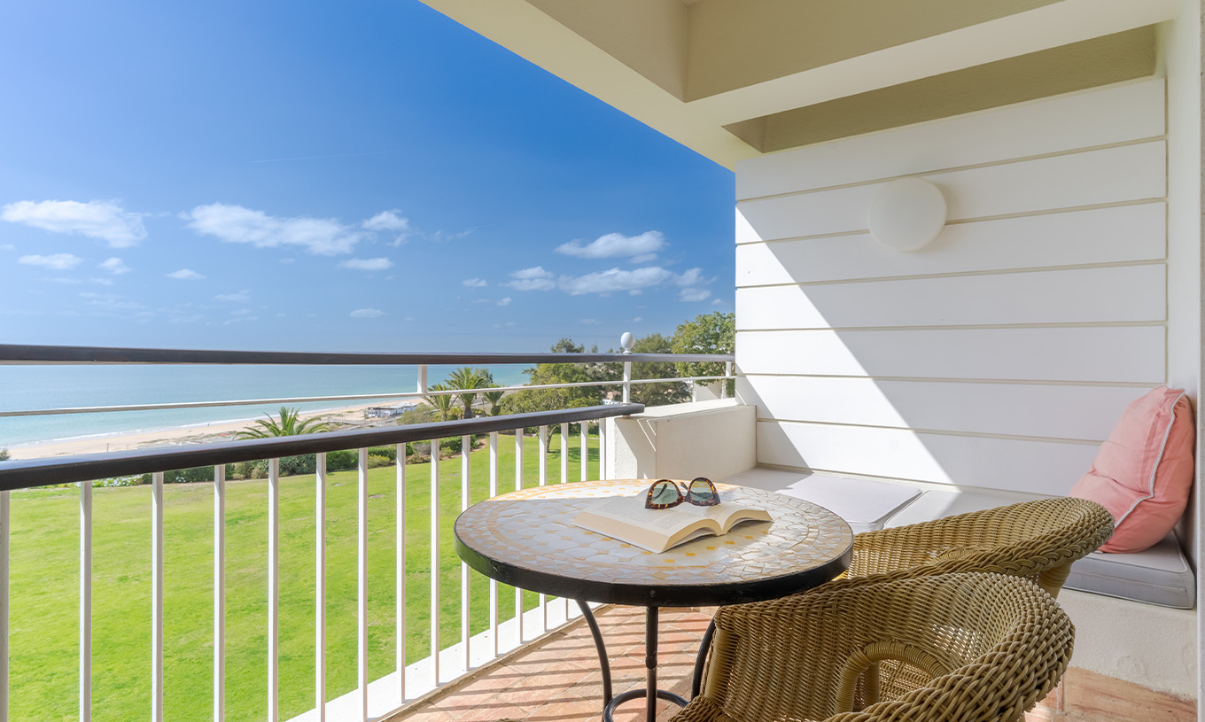 Le Deluxe Vue Mer du Pestana Alvor Praia a balcon avec chaises, table et canapé avec vue sur la mer, plage et jardin