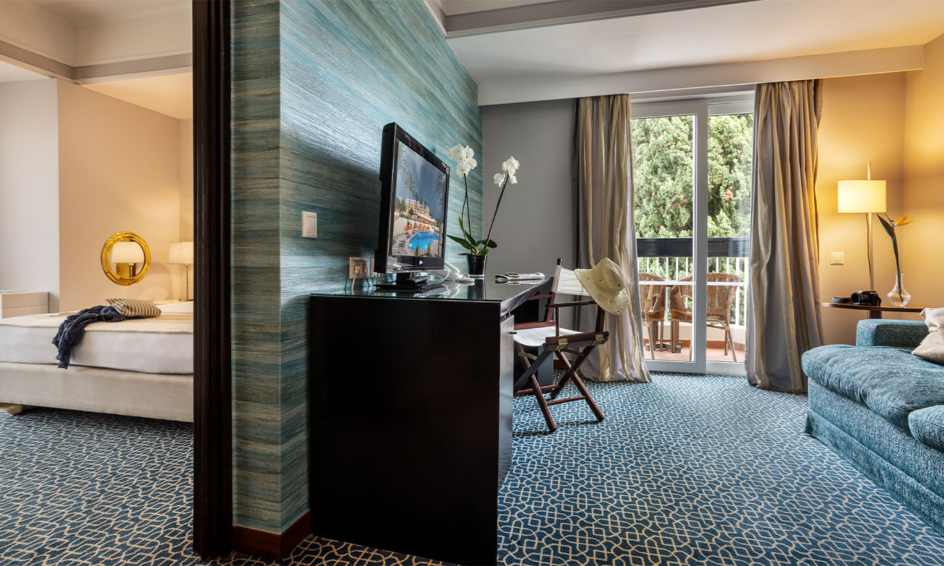 La Suite Vue Jardin du Pestana Alvor Praia a une séparation entre le salon avec canapé, bureau et télévision et la chambre