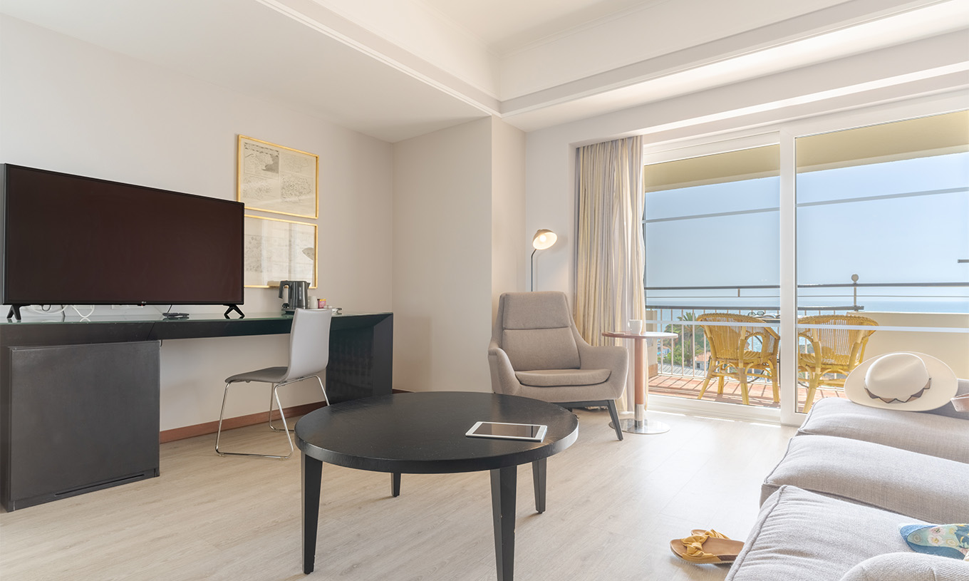 La Suite Vue Mer du Pestana Alvor Praia a un canapé avec table basse, bureau avec télévision et balcon avec vue mer