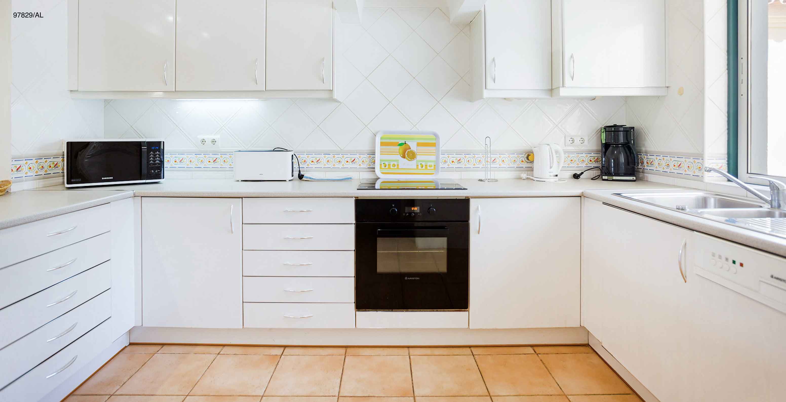 L'appartement Pestana Carvoeiro Golf T2 Standard dispose d'une cuisine avec des armoires blanches et un plan de travail