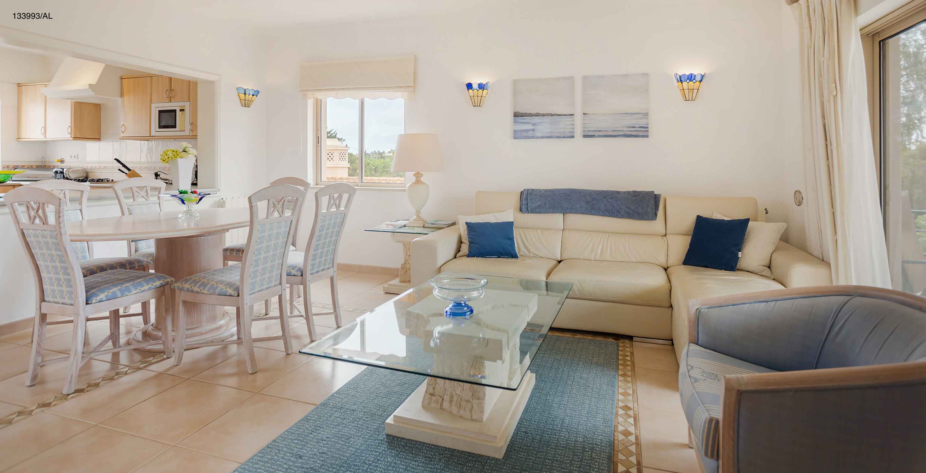 L'appartement Pestana Carvoeiro Golf T2 Superior dispose d'un salon avec un canapé blanc, une table à manger et six chaises