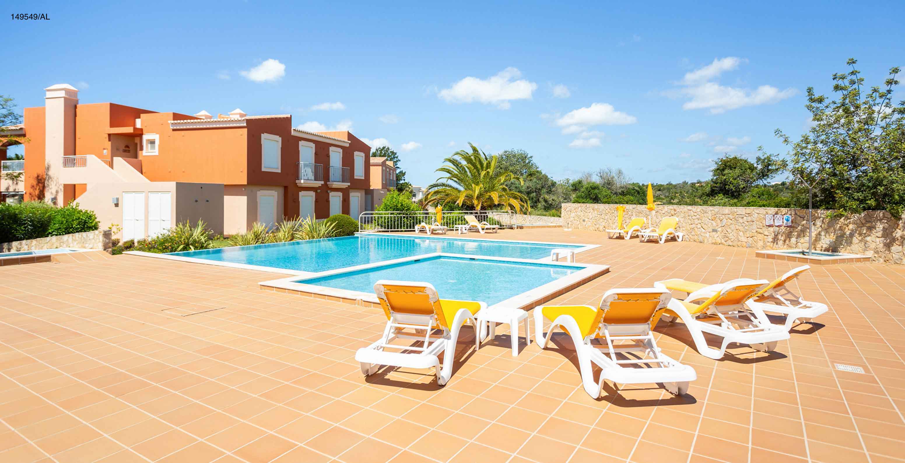 L'appartement Pestana Carvoeiro Golf T2 Superior dispose d'un espace extérieur avec une piscine et des chaises longues jaunes