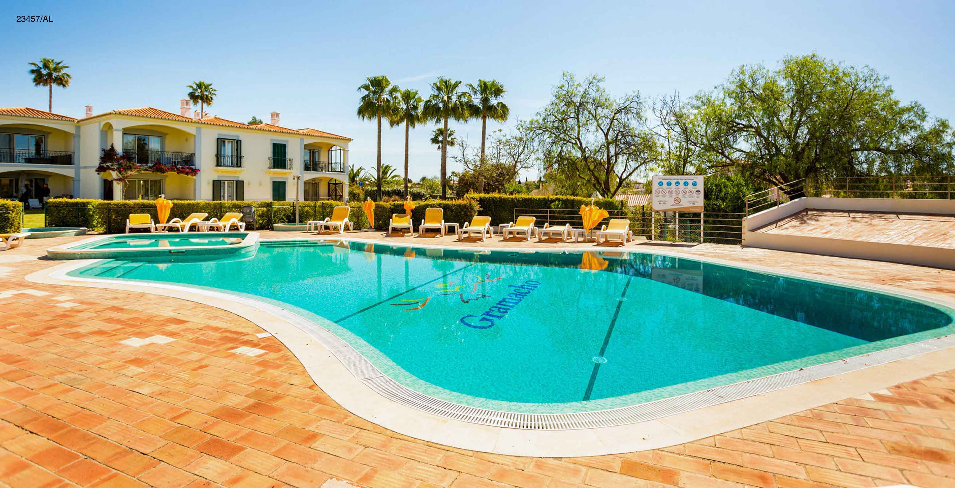 L'appartement Pestana Carvoeiro Golf T3 Standard dispose d'un espace extérieur avec une piscine et des chaises longues jaunes