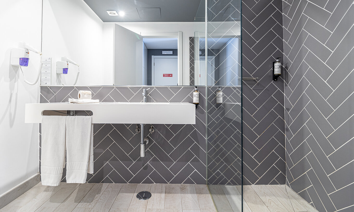 La chambre classique vue piscine a une salle de bain moderne avec lavabo blanc, miroir et douche vitrée