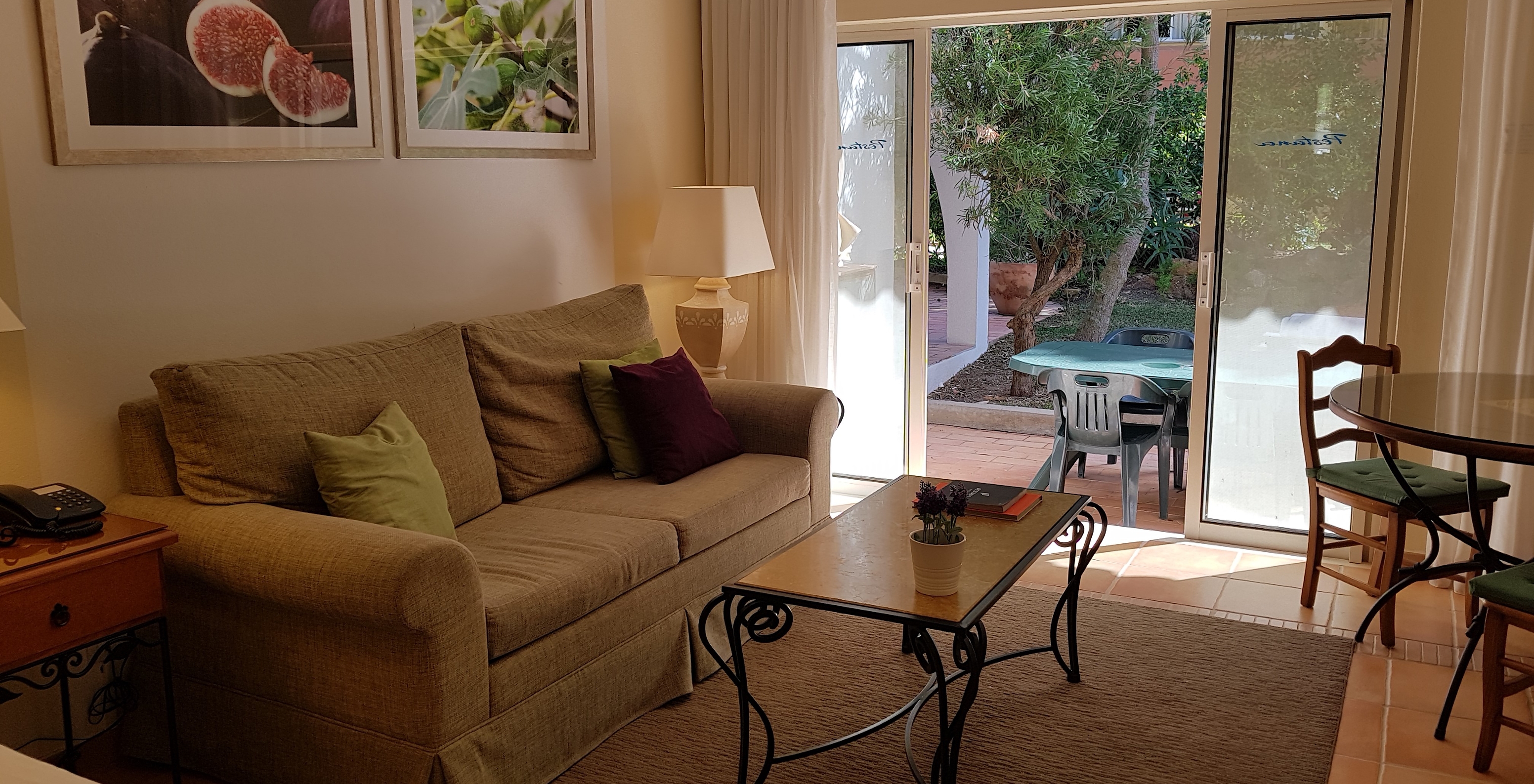 L'Étude du Pestana Palm Gardens a un salon avec canapé et une fenêtre donnant accès au jardin
