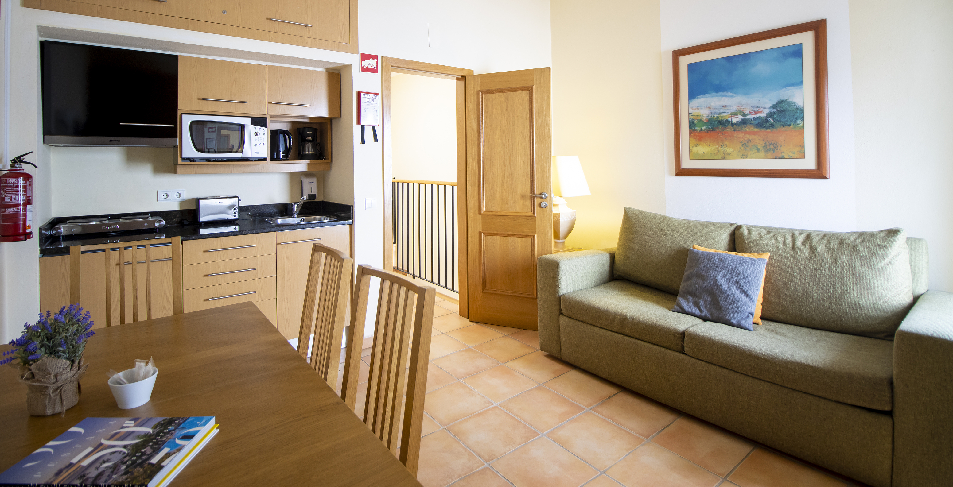 L'Appartement T1 - Terra du Pestana Palm Gardens a un salon avec canapé, table et kitchenette avec micro-ondes