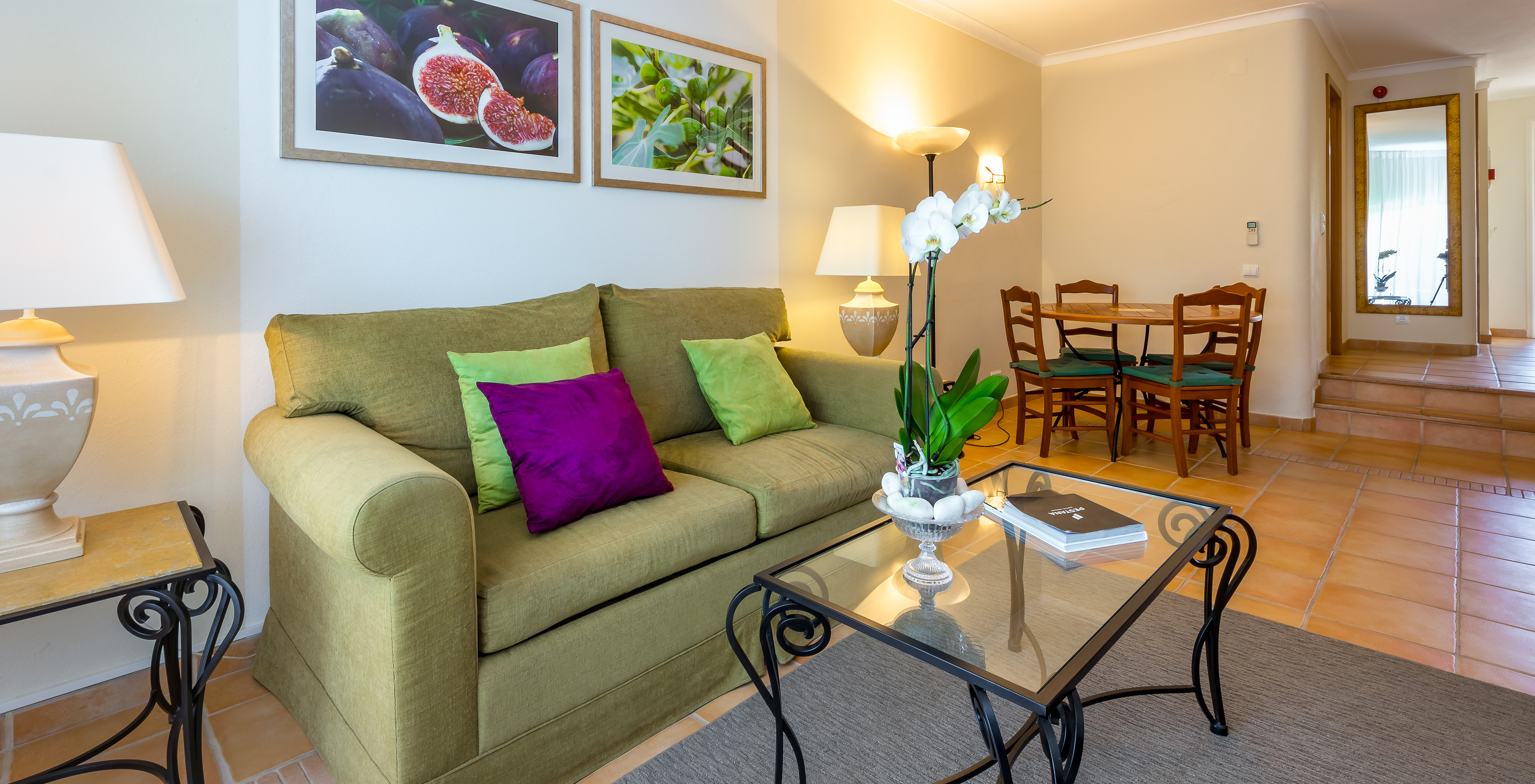 L'Appartement T2 Standard du Pestana Palm Gardens a un salon avec canapé et coussins, une table ronde et des tableaux