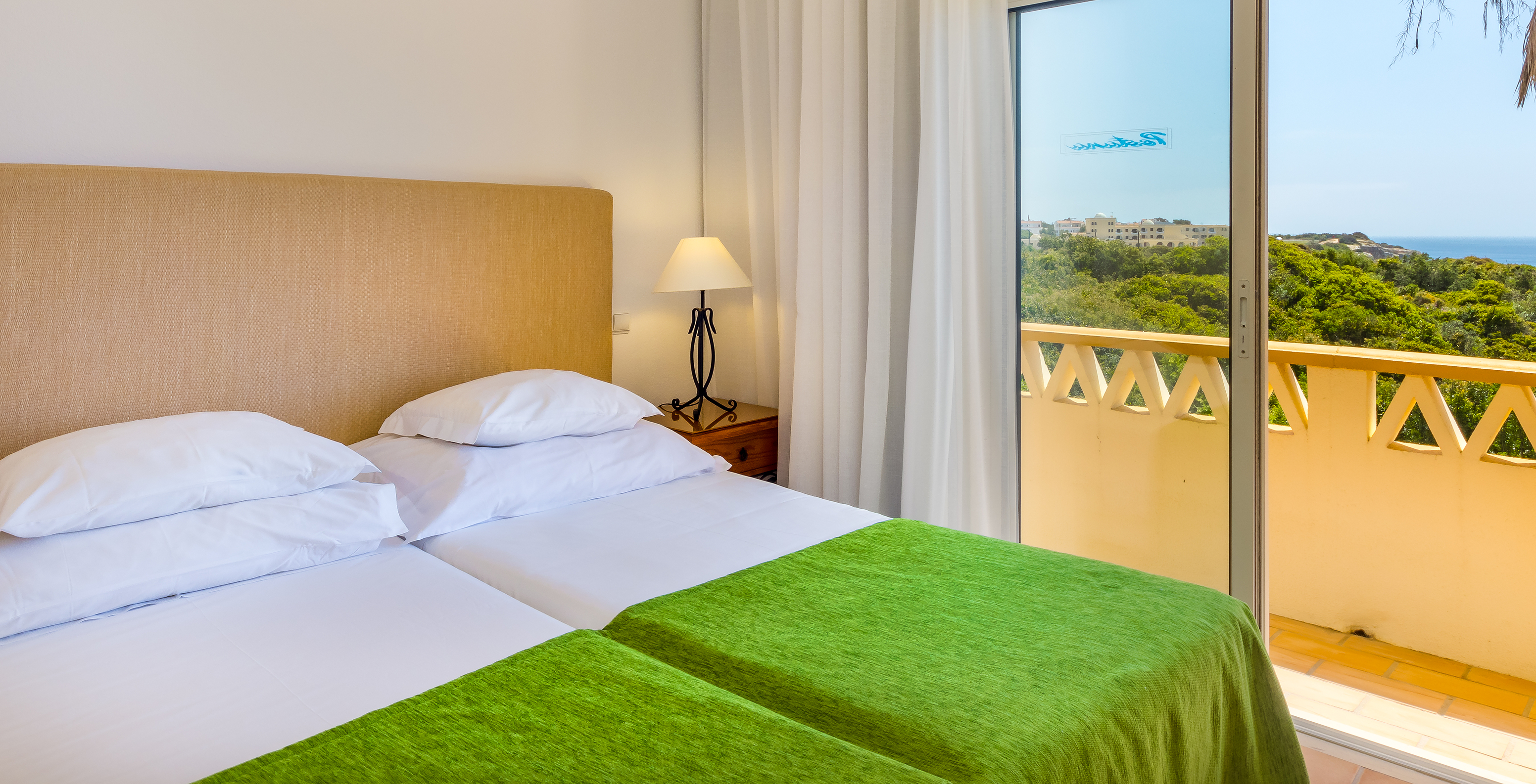 L'Appartement T2 Supérieur du Pestana Palm Gardens a deux lits jumeaux avec couvre-lit vert, un balcon avec vue sur la mer
