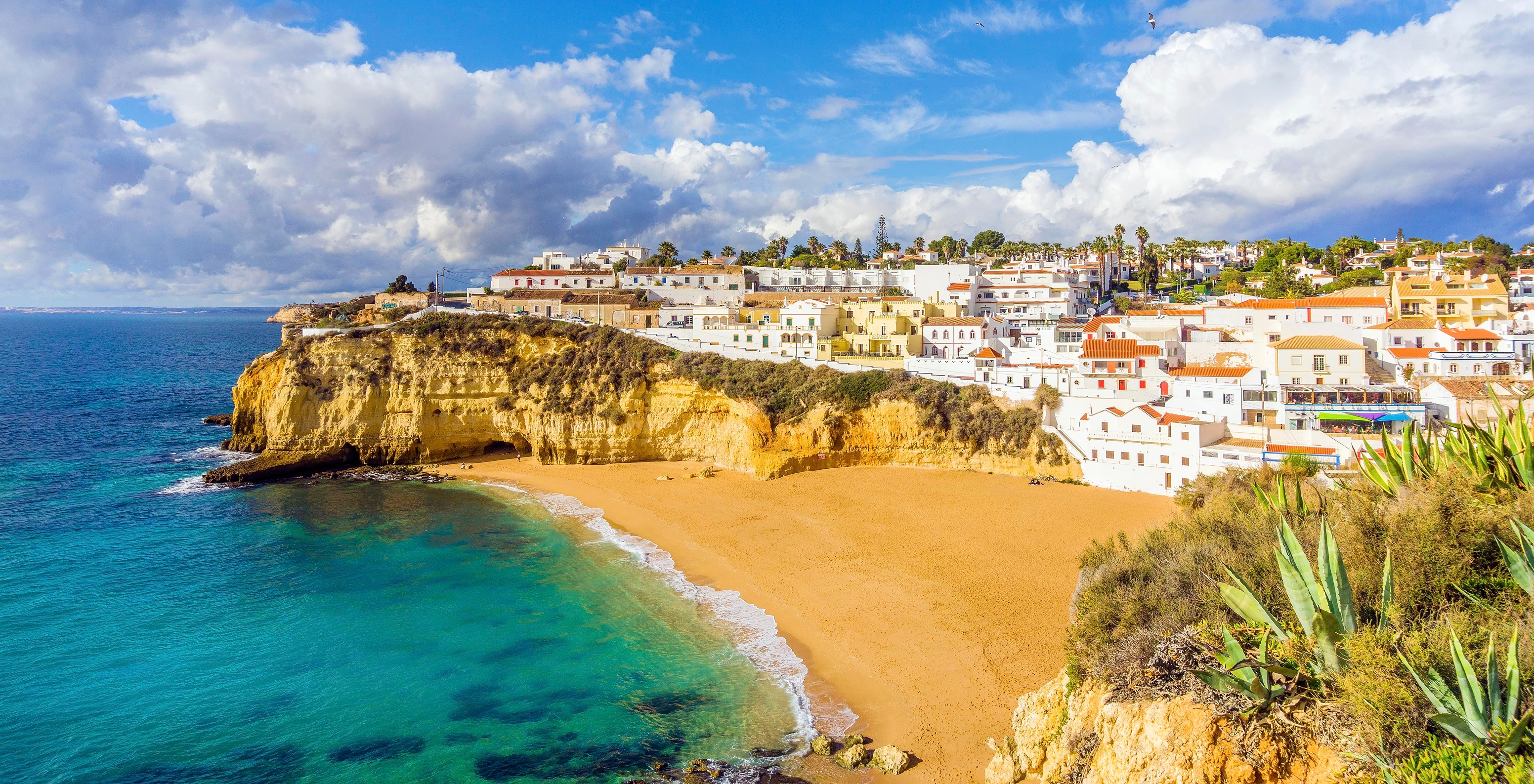 Plage de Carvoeiro, avec eau bleue, falaises typiques de l'Algarve et le village de Carvoeiro en arrière-plan