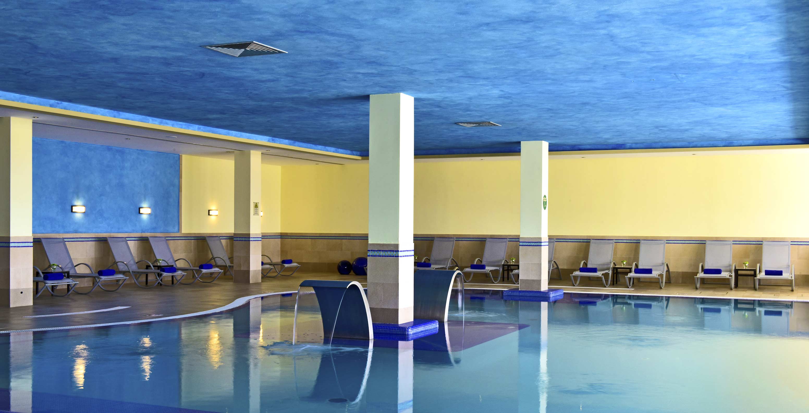 Piscine intérieure du Pestana Viking, murs bleus et jaunes, ambiance calme, avec plusieurs transats