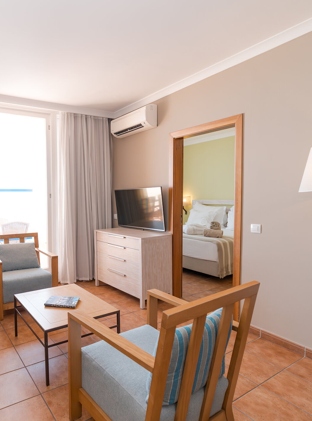 La Suite Vue Mer du Pestana Viking a un salon avec canapé, fauteuils, télévision, climatisation et accès au balcon
