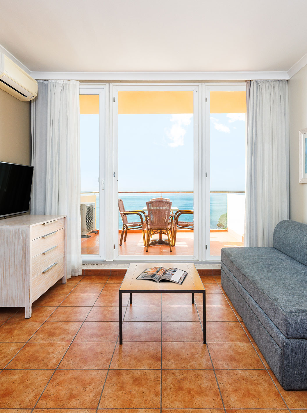 Suite Supérieure Vue Mer du Pestana Viking avec salon lumineux, canapé gris et balcon face à la mer