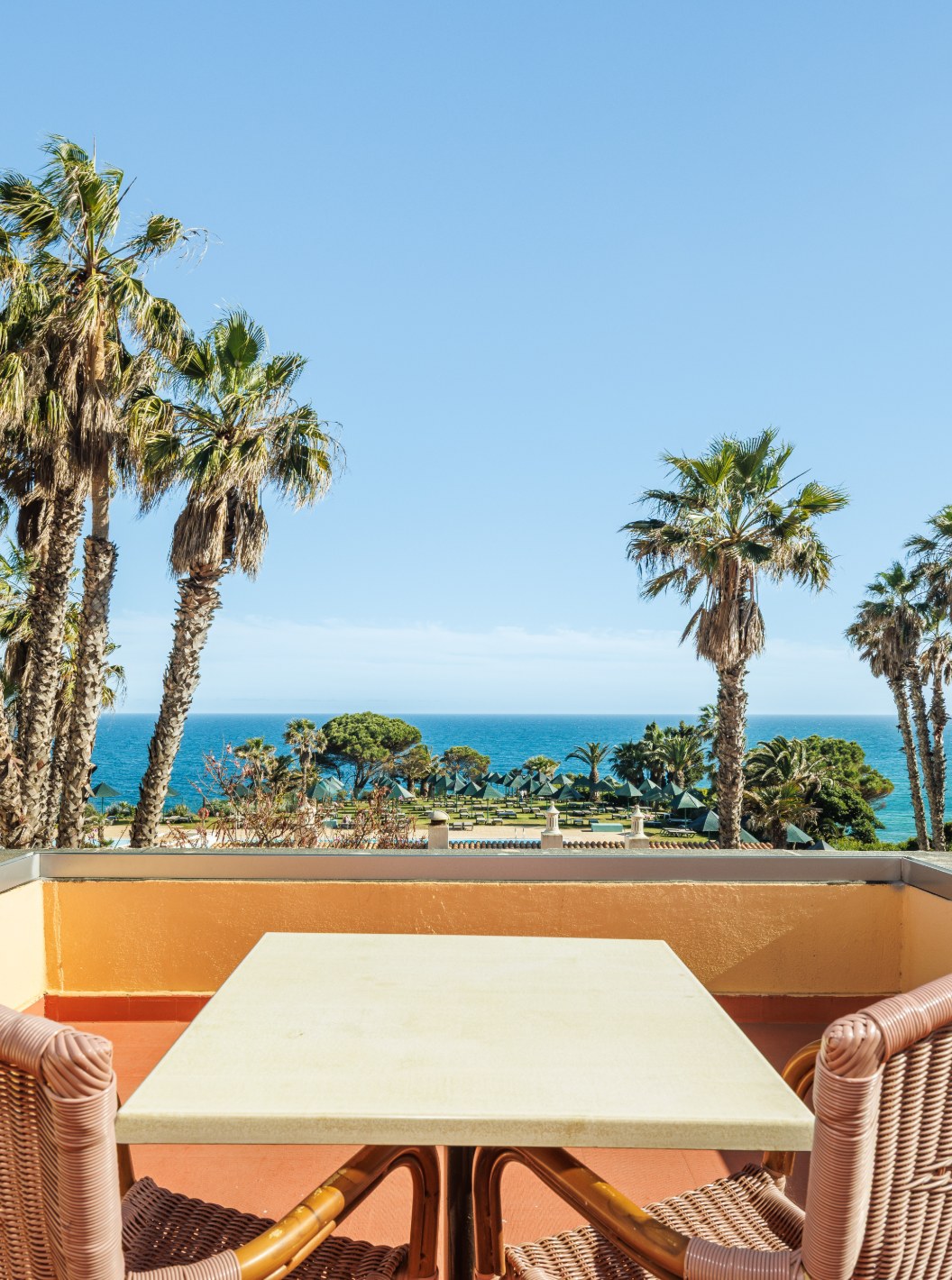 Suite T2 avec vue sur la mer et balcon au Pestana Viking, terrasse avec table face aux palmiers et à l’océan