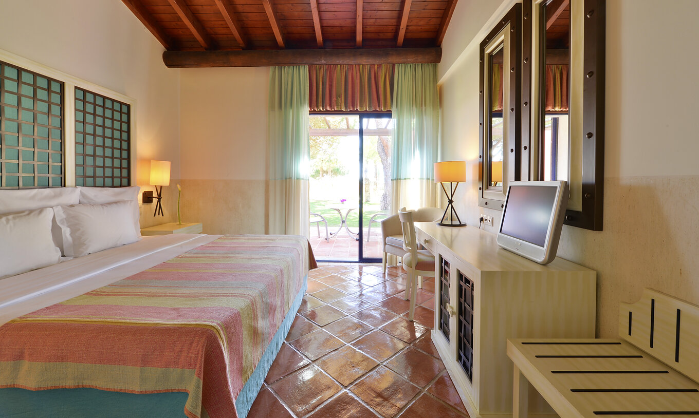 La Suite Vue Jardin Vila Sol du Pestana Vila Sol - Vilamoura dispose d'une chambre avec lit double, miroirs et fenêtre-balcon