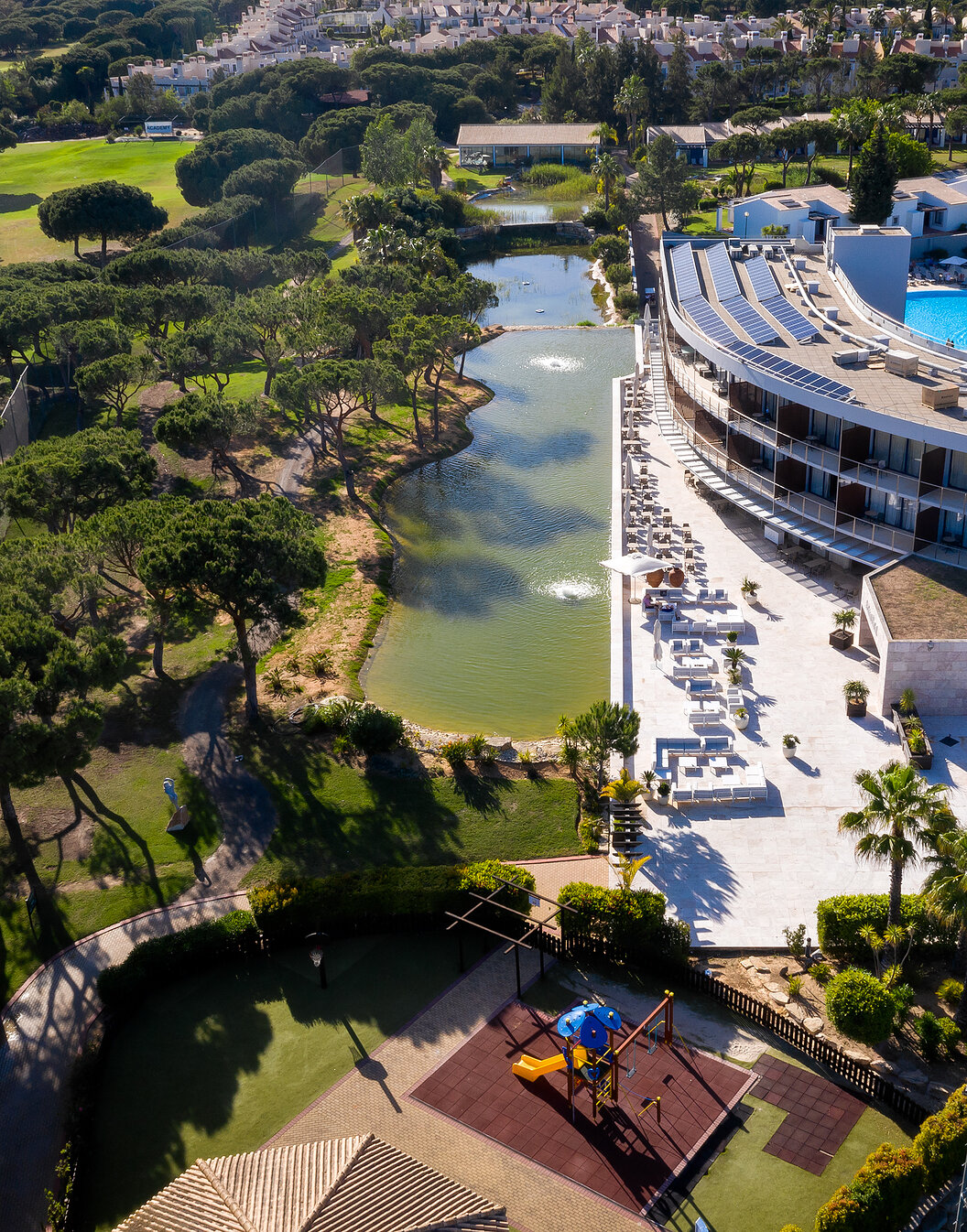Vue du Pestana Vila Sol - Vilamoura, un hôtel 5 étoiles à Vilamoura avec piscine, entouré d'un lac et de verdure