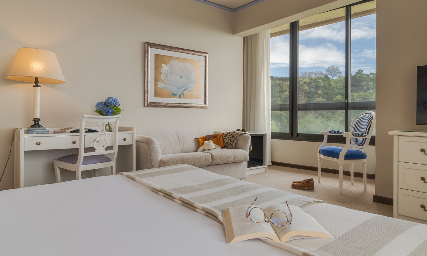 Le Standard Vista Mar du Pestana Bahia Praia a un bureau un canapé et une chaise près de la fenêtre avec vue sur le jardin