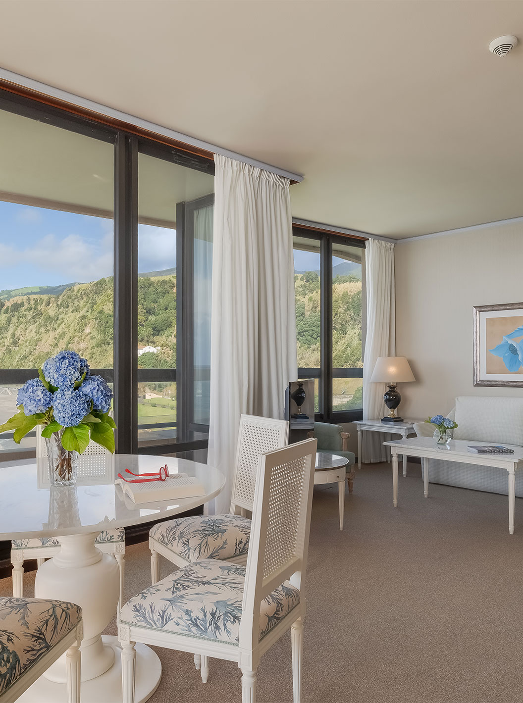 La Suite du Pestana Bahia Praia a un salon avec vue sur la plage à côté de l'hôtel et sur le paysage verdoyant