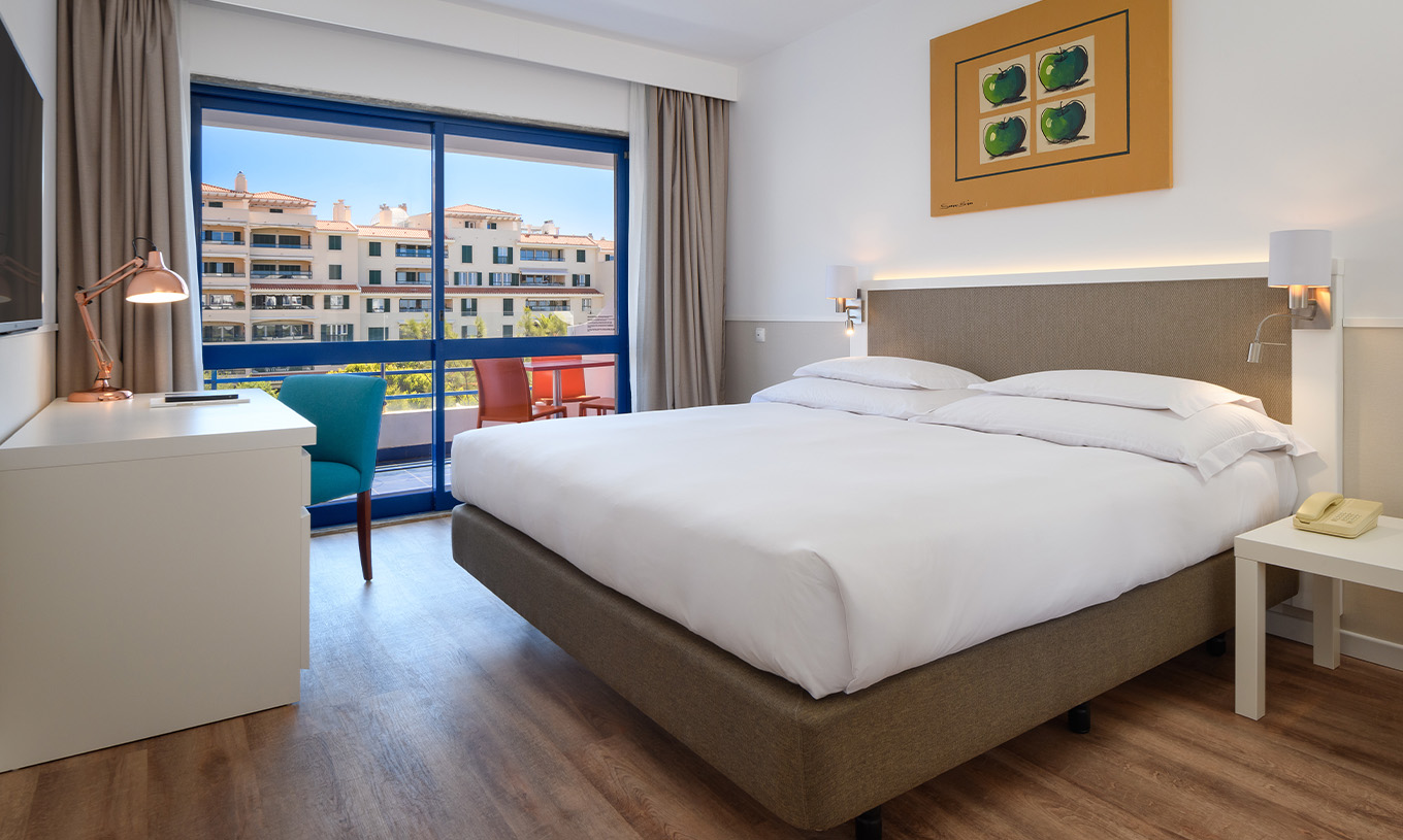 La Suite Deluxe du Pestana Cascais a un lit double, bureau et un tableau peint au mur