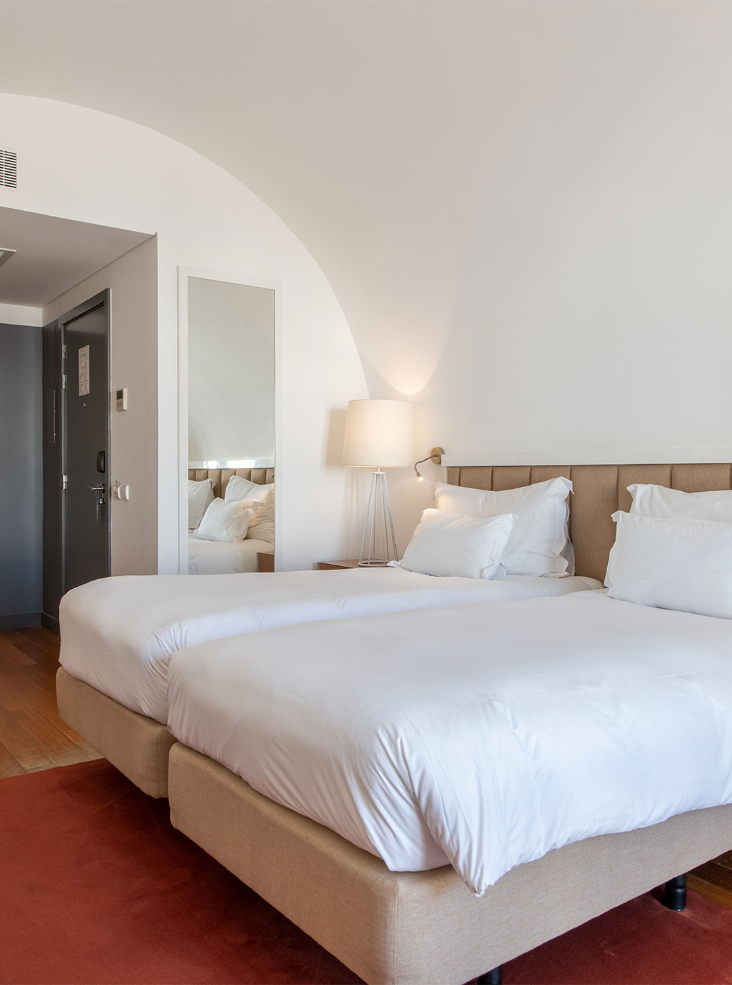 La Chambre Classique du Pestana Cidadela Cascais a deux lits simples, un tapis rouge et un grand miroir élégant