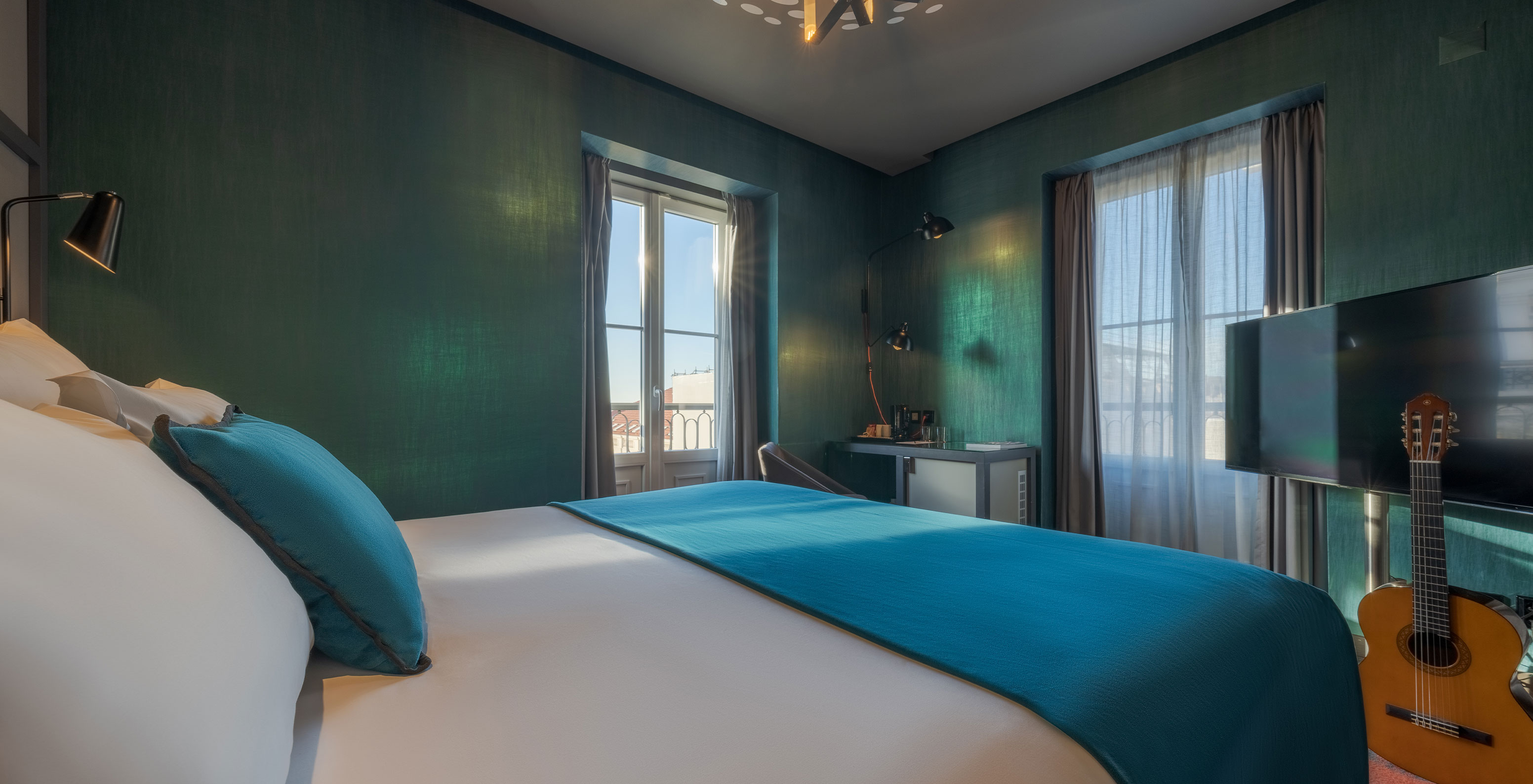 La chambre CR7 Superior Corner du Pestana CR7 Lisboa a un lit et deux fenêtres avec vue sur le Centre Historique