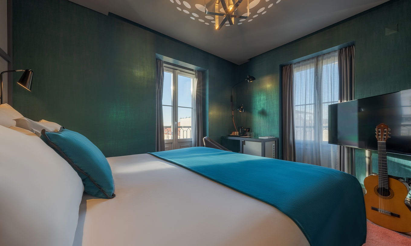 La chambre CR7 Superior Corner du Pestana CR7 Lisboa a un lit et deux fenêtres avec vue sur le Centre Historique