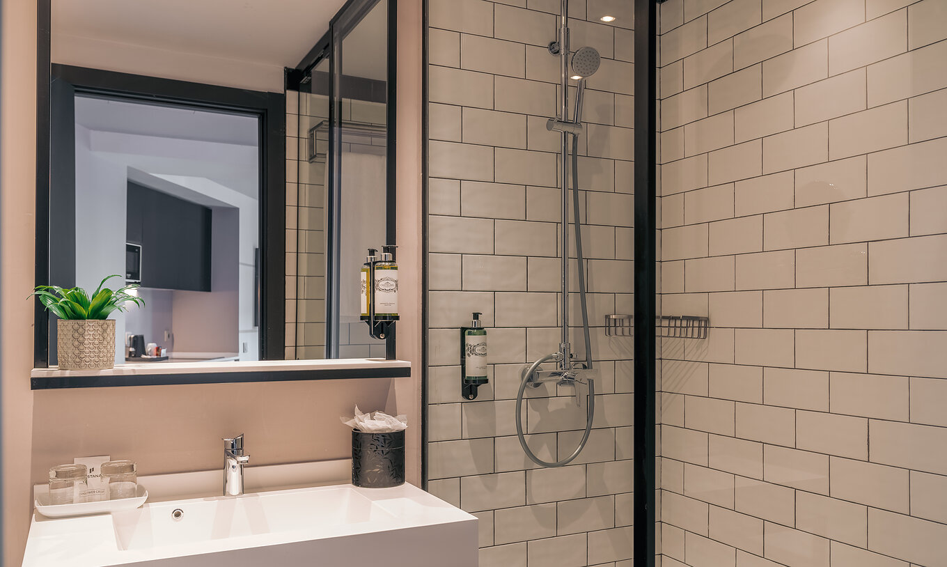 Le Double Deluxe Studio du Pestana Lisboa Vintage a une douche avec portes en verre et détails noirs et un lavabo