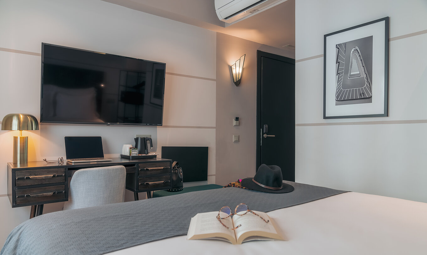 Le Vintage du Pestana Lisboa Vintage a un lit double avec une couverture grise un bureau avec ordinateur et télévision