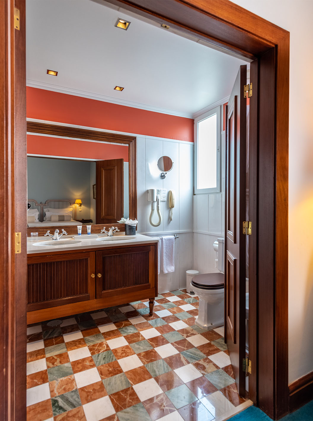 Le Deluxe du Pestana Palace Lisbonne a une salle de bain avec deux lavabos en meuble en bois, miroir et WC