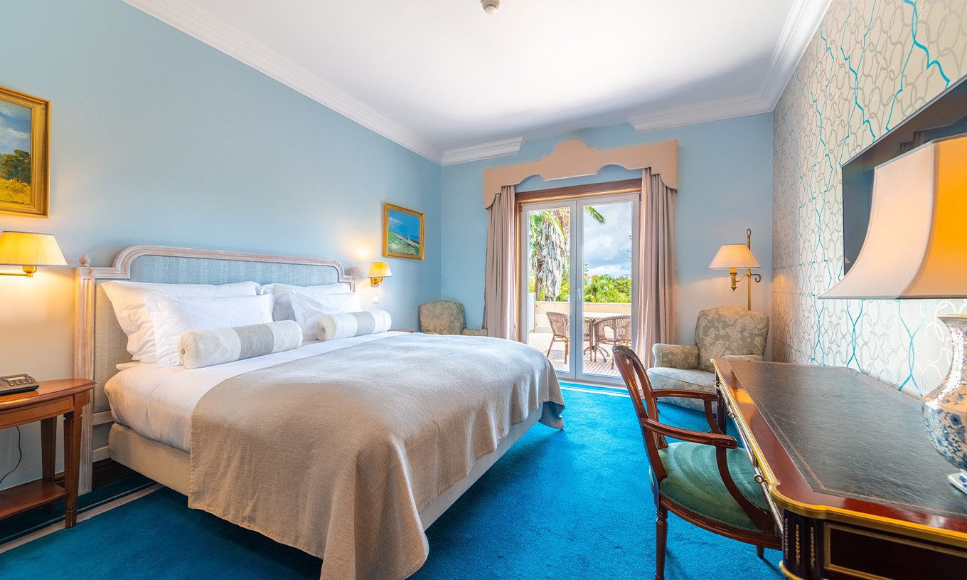 Le Premium Balcony du Pestana Palace Lisbonne a un lit double, murs peints en bleu clair et une fenêtre avec rideaux